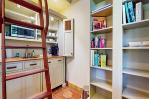 A kitchen with a microwave, coffee maker, and a wooden ladder. - Serene Studio 1st-Floor - Deck - Kitchenette (Seattle)