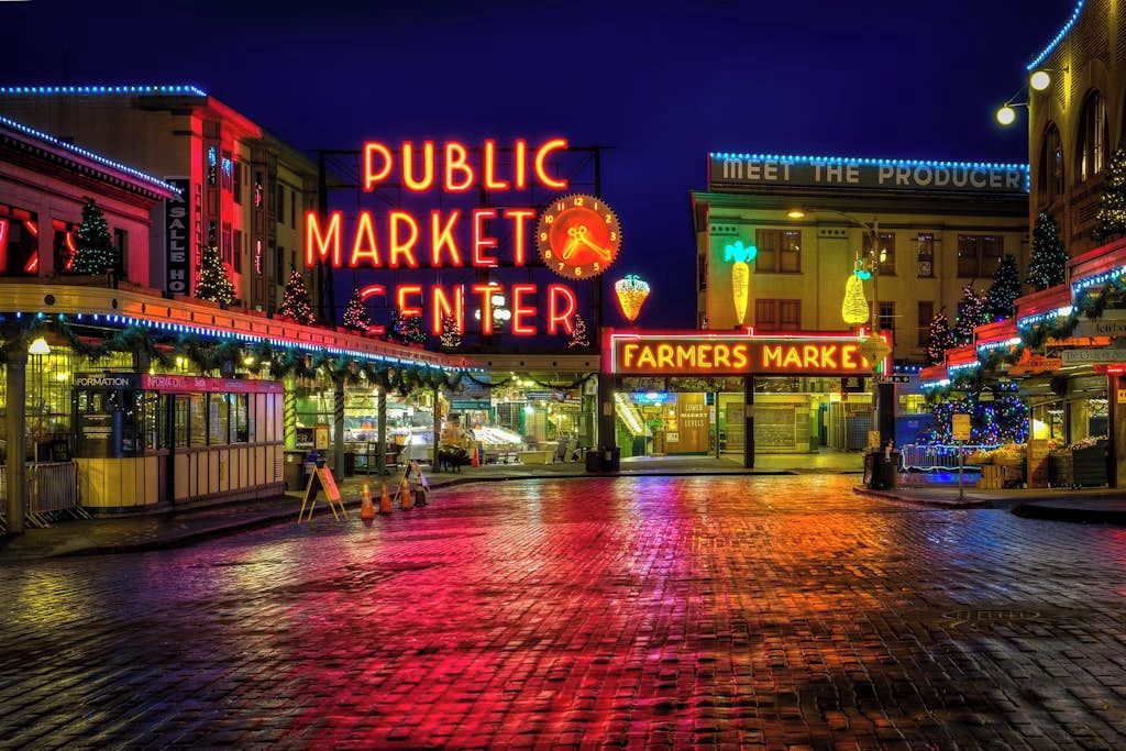 Un marché public illuminé la nuit, avec des enseignes lumineuses et des décorations festives.