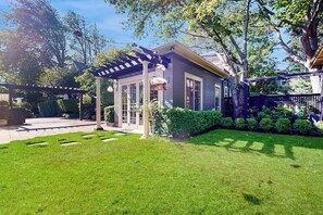 A house with a covered patio, a well-maintained lawn, and a fenced backyard. - Serene Studio 1st-Floor - Deck - Kitchenette (Seattle)