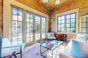 A spacious room with large sliding glass doors, a glass coffee table, and a white sofa. - Serene Studio 1st-Floor - Deck - Kitchenette (Seattle)