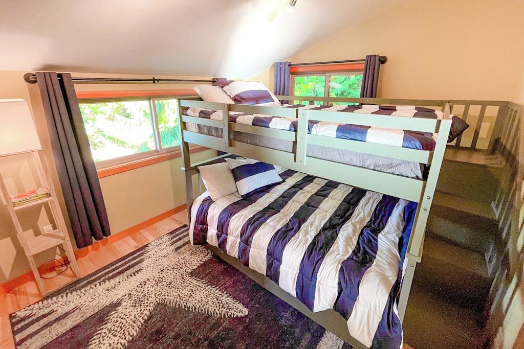 A bunk bed room with a window, a desk, and a patterned rug. - Stunning 3BR Oceanfront Dog Friendly - Dock (Tahuya)