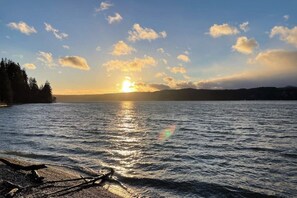 A calm body of water reflecting sunlight with a clear sky and distant landforms. - Stunning 3BR Oceanfront Dog Friendly - Dock (Tahuya)