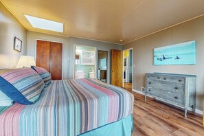 Ein Schlafzimmer mit einem Bett, einem Schminktisch, einem Oberlicht und einem Bild an der Wand.