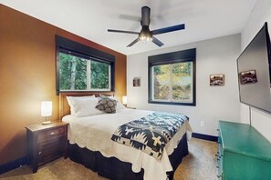 A bedroom with a bed, nightstands, a ceiling fan, and windows.