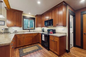 A kitchen with wooden cabinets, a microwave, a stove, and a window. - 2BR withLoft Riverfront-Gas Grill-Wood Stove-Big Yard (Tahuya)