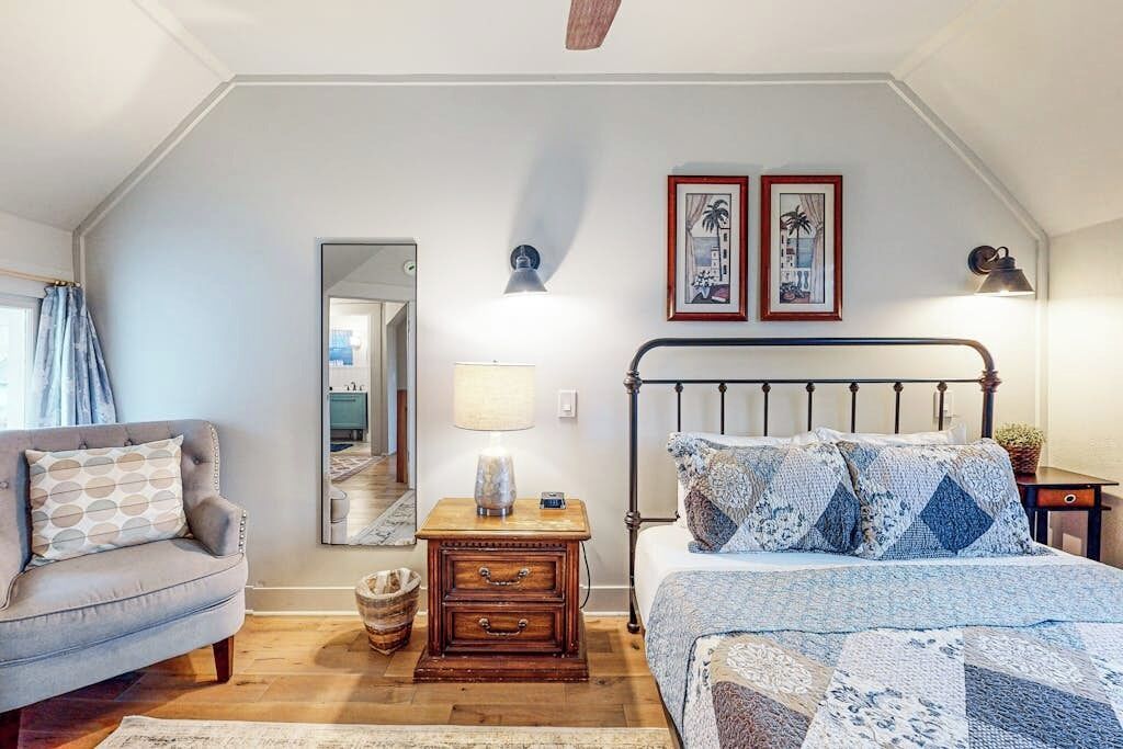 Een slaapkamer met een bed, nachtkastje, lamp, spiegel en een bank.