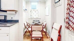 Una cocina compacta con comedor, piso de madera y muebles de cocina blancos.