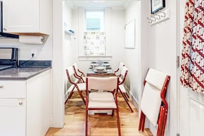 Una cocina compacta con comedor, piso de madera y muebles de cocina blancos.