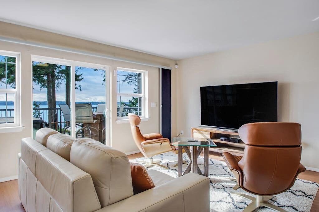 Un salon moderne comprenant un canapé, des fauteuils, une table basse et un téléviseur à écran plat.
