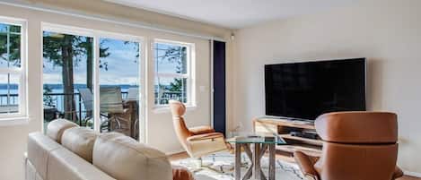 Un salon moderne comprenant un canapé, des fauteuils, une table basse et un téléviseur à écran plat.