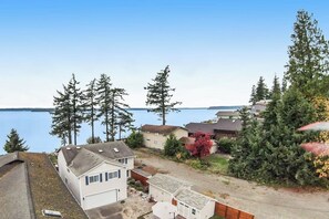 A residential area with houses, a driveway, and a body of water in the background. - Luxury 4BR Oceanfront - Chef's Kitchen- Pool (Tulalip)