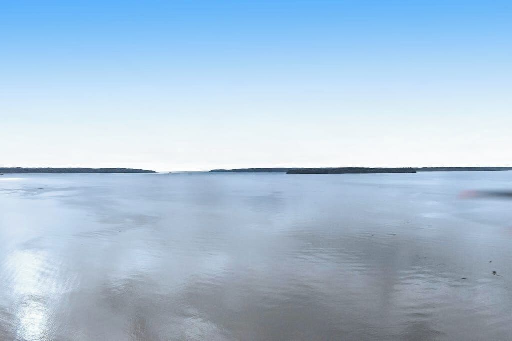 A flat, expansive water body with distant landforms under a clear sky.