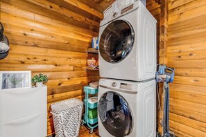 A laundry room with two stacked washing machines, a drying rack, and a small shelf with items. - Dog-friendly 2BR lakefront cabin with amazing view (Tahuya)