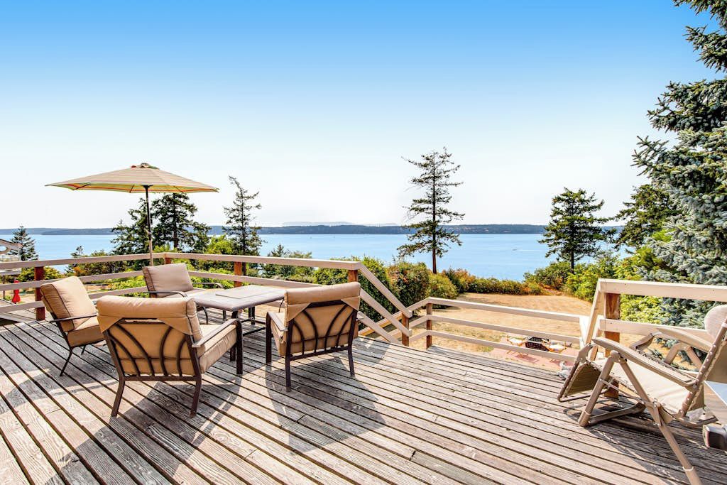 Eine Holzterrasse mit Gartenmöbeln und Blick auf das Wasser.