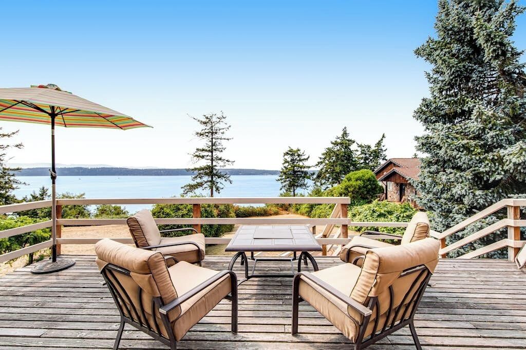 A wooden deck with outdoor furniture and a view of the water.