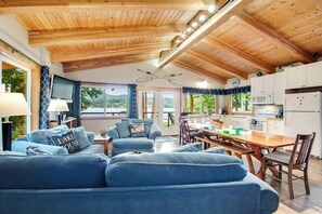 A modern kitchen with wooden cabinets, a dining table, and a view of the outdoors. - 2BR Lakefront - Dock - WoodStove - Deck (Bellingham)