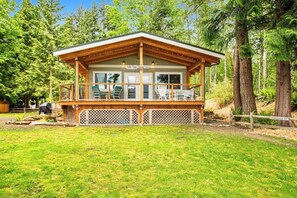 Une cabane dotée d  ’une terrasse couverte, de grandes fenêtres et offrant une vue sur la forêt environnante.