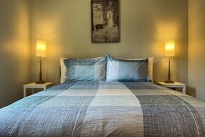 A bed with a checkered bedspread, two bedside lamps, and a framed picture on the wall. - 4BR Home with fire pit & pickleball and basketball court (Cle Elum)