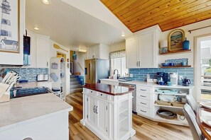Une cuisine moderne avec des meubles blancs, un plafond en bois et un pare-feu bleu.