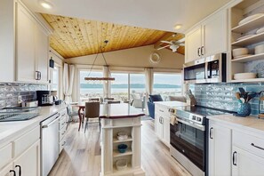 A modern kitchen with a wooden ceiling, built-in appliances, and a view of the mountains. - 3 BD waterfront home with private beach access (Camano Island)
