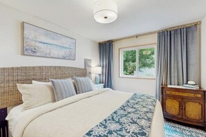 Una camera da letto con un letto, una cassettiera, una lampada e un quadro appeso al muro.
