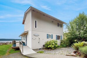A two-story building with a 'Welcome' sign, a deck, and a view of the water. - 3 BD waterfront home with private beach access (Camano Island)