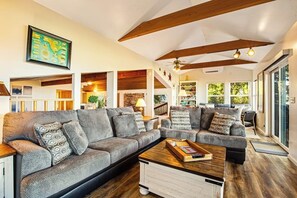 A spacious living room with a large sectional sofa, a coffee table, and a staircase leading to an upper level. - Amazing View 2BR Soundview - Deck (Nordland)