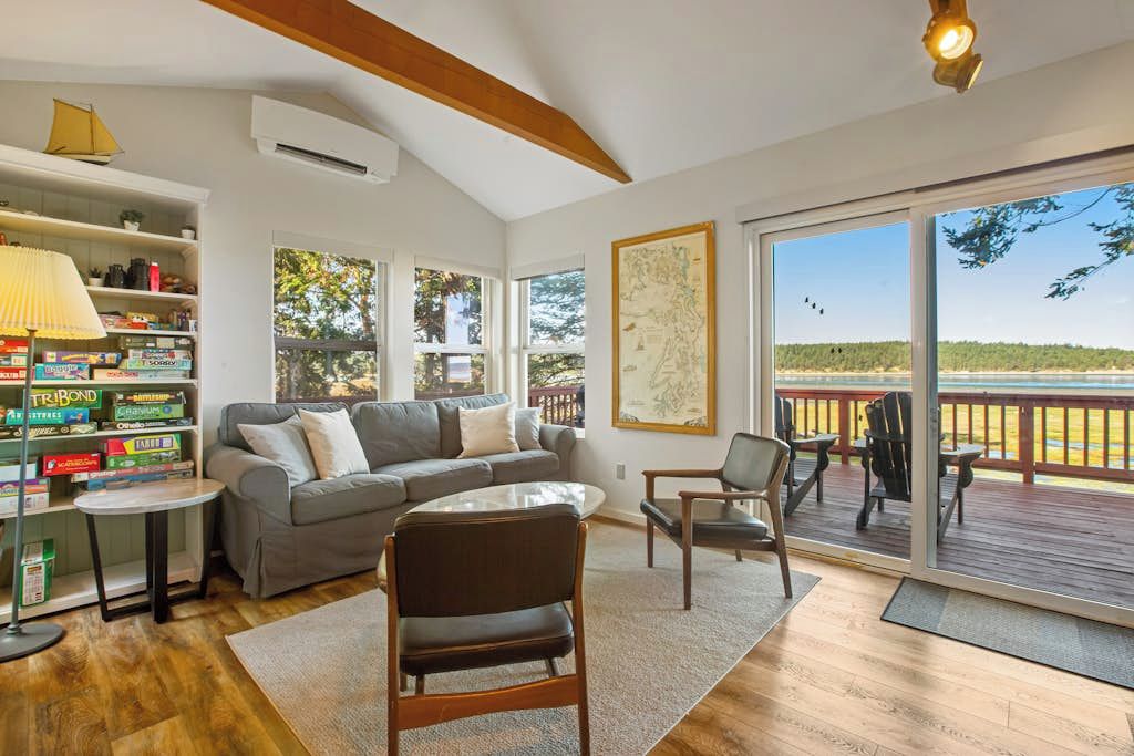 A spacious living room with a gray sofa, a coffee table, and a bookshelf filled with board games.