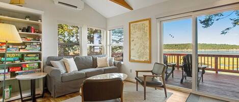 A spacious living room with a gray sofa, a coffee table, and a bookshelf filled with board games.