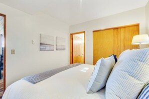 Ett hotellrum med en säng, en trädörr och en väggmonterad lampa.