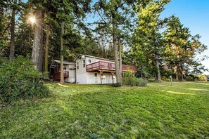 A two-story house with a balcony, surrounded by trees and a grassy yard. - Amazing View 2BR Soundview - Deck (Nordland)