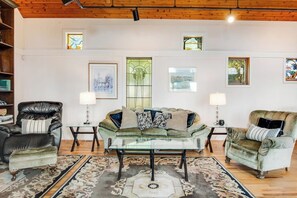 A living room with a sofa set, two armchairs, a coffee table, and a patterned rug.