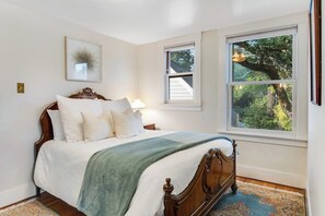 Ein Schlafzimmer mit einem Bett, einem Fenster und einem an der Wand hängenden Bild.