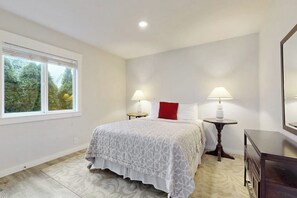 A bedroom with a bed, two bedside tables with lamps, a dresser, and a window with blinds. - Cozy 2BR - Fireplace - Patio - Washer Dryer (Anacortes)