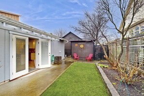 A residential backyard with a lawn, two pink chairs, a shed, and a fence. - Cozy 2BR - Fireplace - Patio - Washer Dryer (Anacortes)