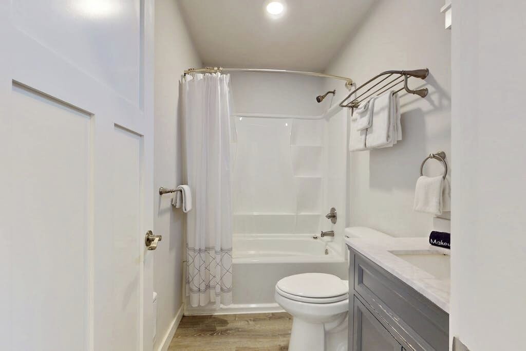 Un baño con ducha, inodoro y tocador.