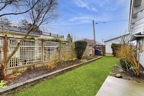 A residential property with a well-maintained lawn, a wooden fence, and a stone border. - Cozy 2BR - Fireplace - Patio - Washer Dryer (Anacortes)