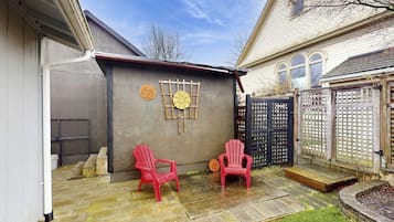 Ein Garten mit zwei roten Stühlen, einer Betonmauer mit Holzwabenstruktur und einem schwarzen Tor.