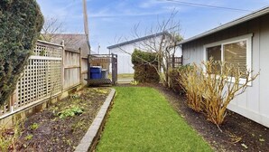 Een achtertuin met gazon, houten schutting en een huis op de achtergrond.