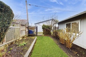 En bostadsträdgård med en gräsmatta, ett trästaket och ett hus i bakgrunden.