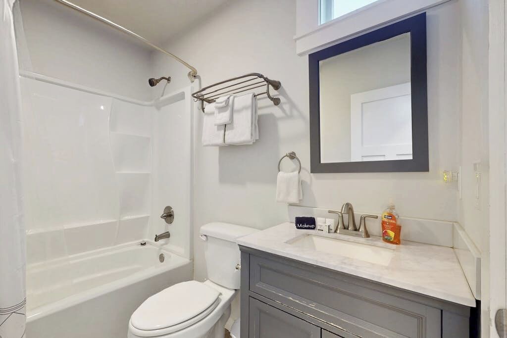Une salle de bain moderne équipée d’une baignoire, de toilettes, d’un meuble-lavabo et d’un grand miroir.