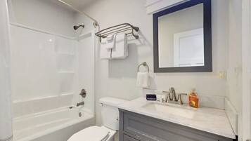 Une salle de bain moderne équipée d’une baignoire, de toilettes, d’un meuble-lavabo et d’un grand miroir.