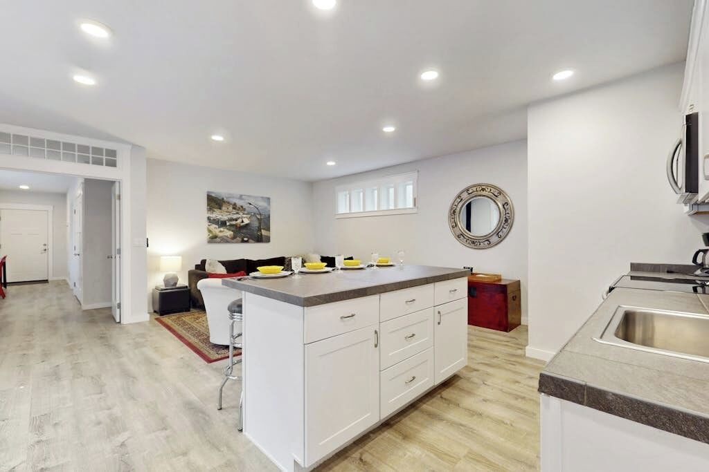 Una cocina moderna con armarios blancos, una isla central y un lavamanos integrado.