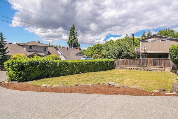 Ein Wohnhaus mit gepflegtem Rasen, Holzzaun und blauem Himmel.