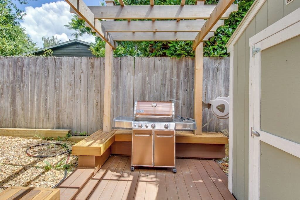 A barbecue grill with a wooden deck and a wooden fence in the background.