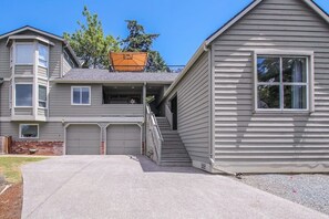 Un immeuble résidentiel à deux étages doté d’un patio couvert, d’un garage et d’un escalier apparent menant à l’étage supérieur.
