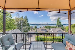 A covered outdoor seating area with a view of a lake and houses. - Cozy Studio Lakeview - Deck - NoKitchen- Shared Hot Tub (Mercer Island)
