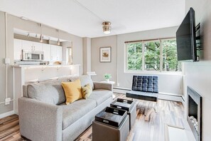 A modern living room with a grey sofa, a black ottoman, and a flat-screen TV mounted on the wall. - City 1BR Washington State Conv. Center 12th-Floor (Seattle)