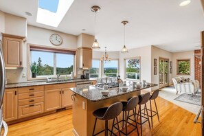 A spacious kitchen with a large island, wooden cabinets, and a skylight.