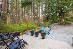 An outdoor seating area with tables and chairs, surrounded by a forest. - Gorgeous 1BR - Patio - Firepit - Washer Dryer (Camano Island)